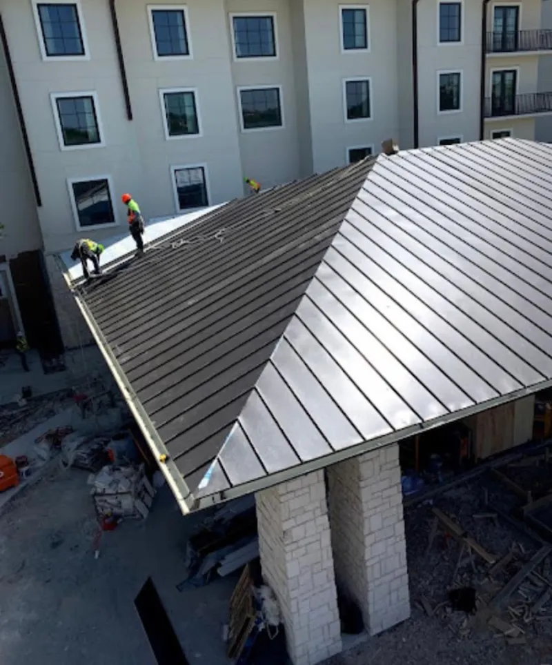 Crew installing standing seam metal roof panels on a commercial project in Orland